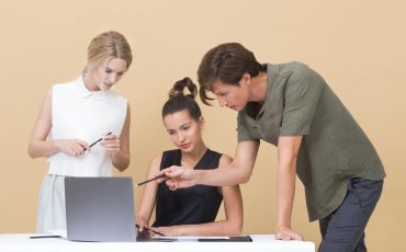 Group of professionals collaborating on a project, discussing ideas around a laptop.